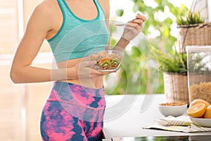 Young woman in fitness clothes having healthy breakfast