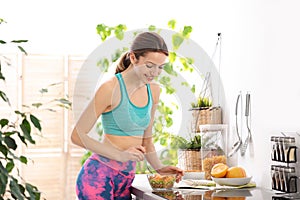 Young woman in fitness clothes having healthy breakfast