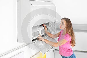 Young woman fixing air conditioner