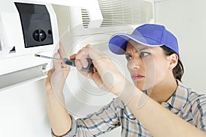 young woman fixing air conditioner at home