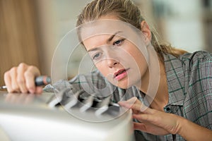 young woman fixing air conditioner at home