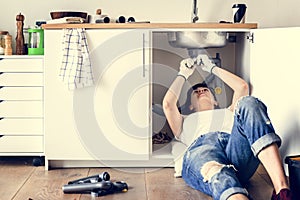 Young woman fixing kitchen sink