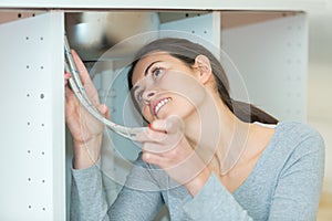 young woman fixing sink pipe in kitchen