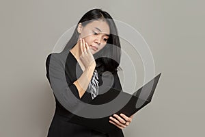 Young woman with a flat facial expression while looking at and holding a folder