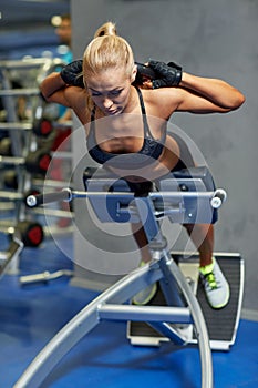 Young woman flexing back muscles on bench in gym