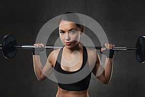 Young woman flexing muscles with barbell in gym