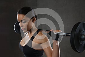 Young woman flexing muscles with barbell in gym