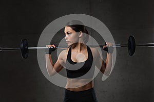 Young woman flexing muscles with barbell in gym