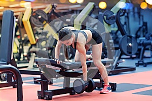 Young woman flexing muscles with dumbbell in gym