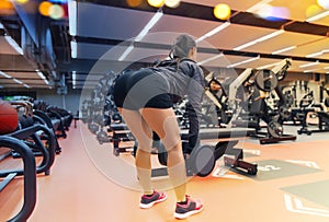 Young woman flexing muscles with dumbbells in gym