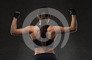 Young woman flexing muscles in gym