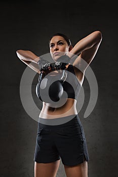 Young woman flexing muscles with kettlebell in gym