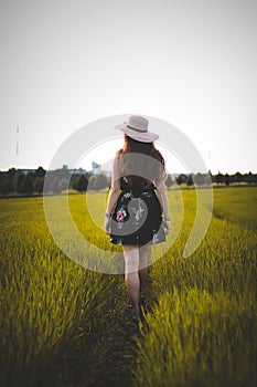 Young woman in a floral dress walks through a green field near Beskydy mountains. Candid portrait of a wonderful woman raking her