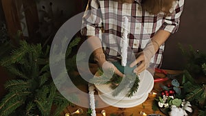 Young woman florist creating Christmas flower arrangement in flower shop studio.