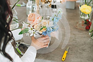 Young woman florist in white with bouquet of flowers in box in flower shop, small local business owner. Young stylish success