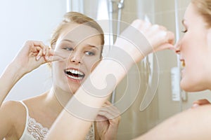 A young woman flossing her teeth