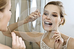 A young woman flossing her teeth