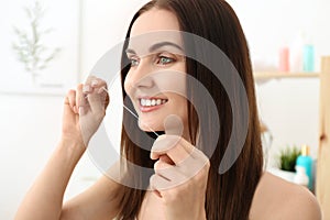 Young woman flossing her teeth in bathroom