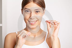 Young woman flossing her teeth in bathroom