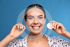 Young woman flossing her teeth on blue background. Cosmetic dentistry