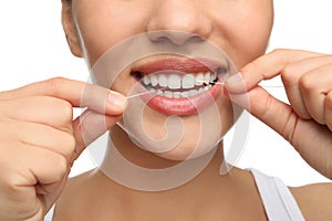 Young woman flossing her teeth on white background, closeup. Cosmetic dentistry