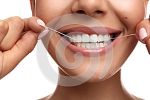 Young woman flossing her teeth on white background, closeup. Cosmetic dentistry