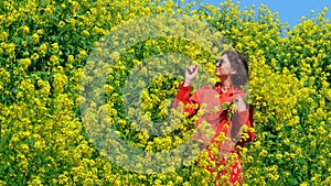 A young woman in a flower spring field sniffs flowers and is happy