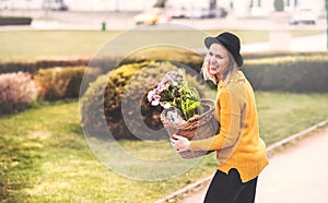 Young woman with flowers in a basket in sunny spring town.