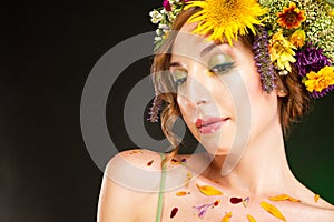 Young woman with flowers in her hair and petals on the body.