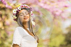 Young woman with flowers in her hair on sunny spring day