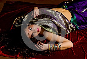Young woman with flowing hair dressed in beautiful Indian sari lies on the bright red velvet