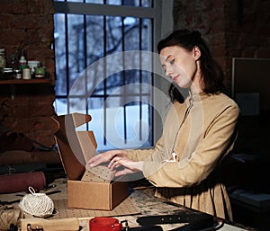 Young woman folds packing box in sewing workshop