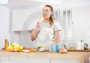 Young woman following healthy diet eating vegetable salad in kitchen