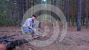 Young woman in forest camping cuts trunk of tree with an axe for firewood.