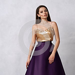 Young woman in formal dress with golden sequin top and purple sa
