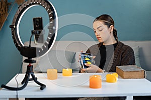 Young woman fortune teller recording video for blog using tarot cards, smartphone and ring lamp, predicts future online