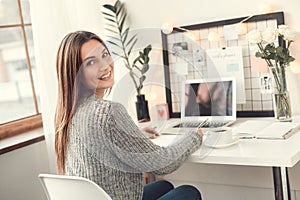 Young woman freelancer indoors home office concept winter atmosphere sitting writing in planner smiling photo