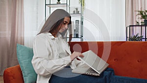 Young woman freelancer sitting on sofa closing laptop pc after finishing work in living room at home