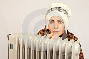 Young woman freezing near the heater