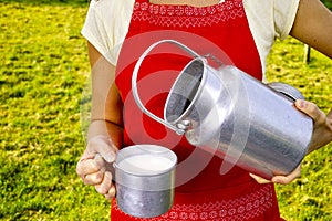 Young woman with fresh organic farm cowmilk in aluminum milk can