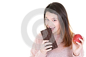 Young woman with fruit and chocolate being tempted but trying to be healthy