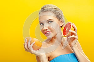 Young woman with fruits on bright orange background