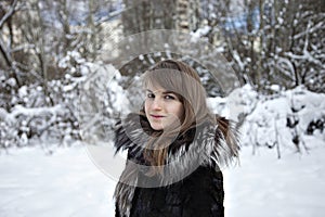 Young woman is in fur coat in the cold in winter in the woods. Close up fase.