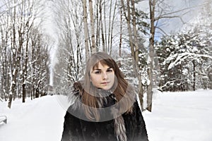 Young woman is in fur coat in the cold in winter in the woods. Close up fase.