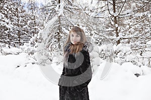 Young woman is in fur coat in the cold in winter in the woods. Close up fase.