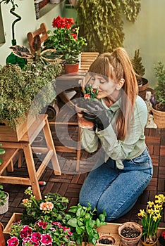 Young Woman Gardener Kneeling on Apartment Balcony