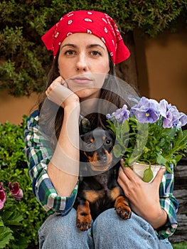 Young Woman Gardening At Home with her little dog teckel