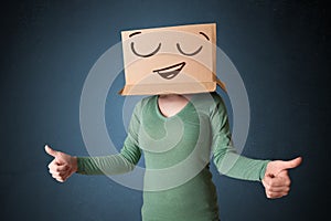 Young woman gesturing with a cardboard box on her head with smiley face