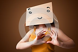 Young woman gesturing with a cardboard box on her head with smiley face