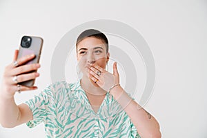 Young woman gesturing and taking selfie photo on cellphone